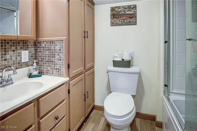 full bathroom featuring toilet, wood finished floors, vanity, baseboards, and backsplash