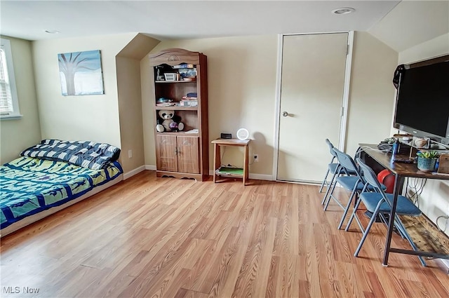 bedroom featuring light wood-style floors, vaulted ceiling, and baseboards