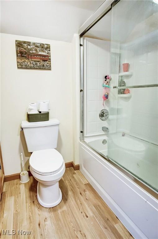 full bathroom featuring bath / shower combo with glass door, baseboards, toilet, and wood finished floors