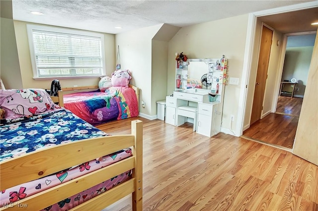 bedroom featuring a textured ceiling, baseboards, and wood finished floors