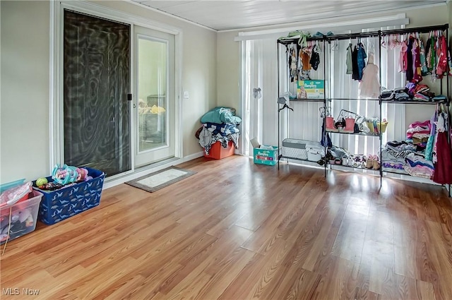 interior space with access to outside, ornamental molding, and wood finished floors