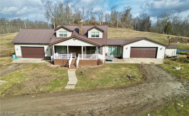 view of front of home featuring a porch, an attached garage, metal roof, driveway, and a front lawn