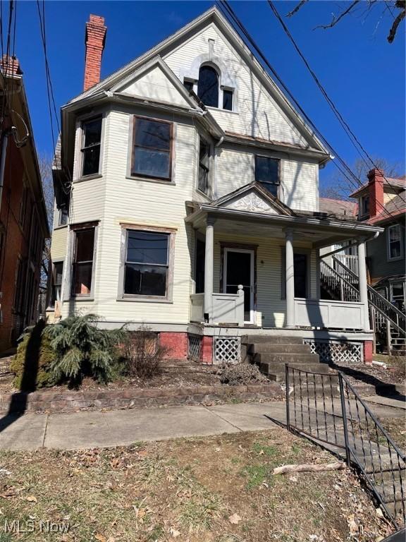 victorian house featuring a chimney and a porch