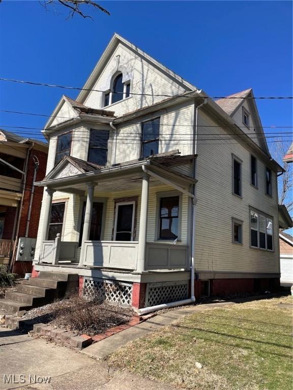 view of side of property with covered porch and a yard