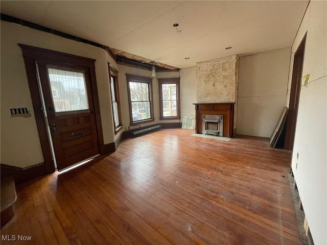 unfurnished living room featuring hardwood / wood-style flooring, a fireplace with flush hearth, and baseboards