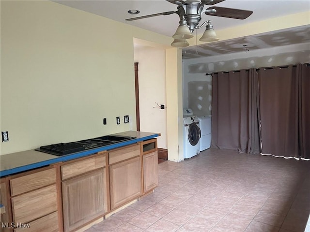 kitchen featuring washing machine and clothes dryer, dark countertops, a ceiling fan, stovetop with downdraft, and light tile patterned flooring