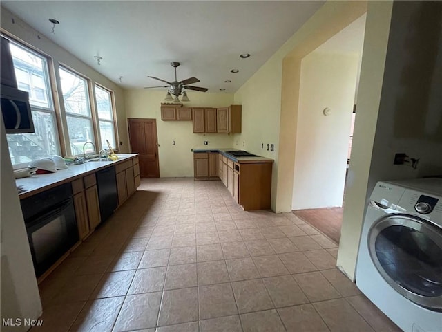 kitchen featuring light tile patterned floors, washer / clothes dryer, a ceiling fan, a sink, and black appliances