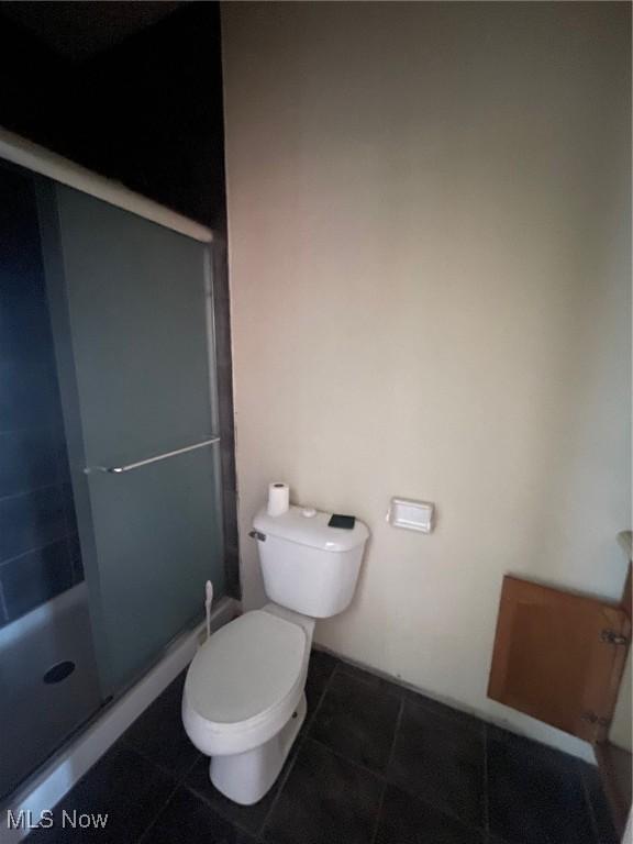 full bathroom featuring a shower stall, toilet, and tile patterned floors