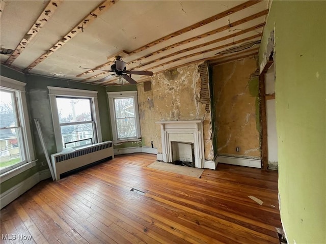 unfurnished living room with a fireplace with flush hearth, radiator, ceiling fan, and hardwood / wood-style floors