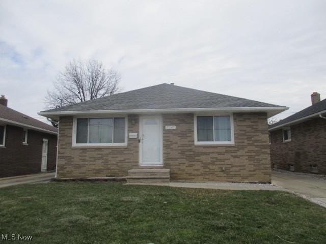 view of front of house with a shingled roof, entry steps, and a front yard