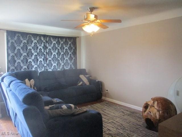 living room featuring baseboards, a ceiling fan, and wood finished floors