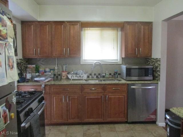 kitchen with brown cabinets, backsplash, stainless steel appliances, and a sink