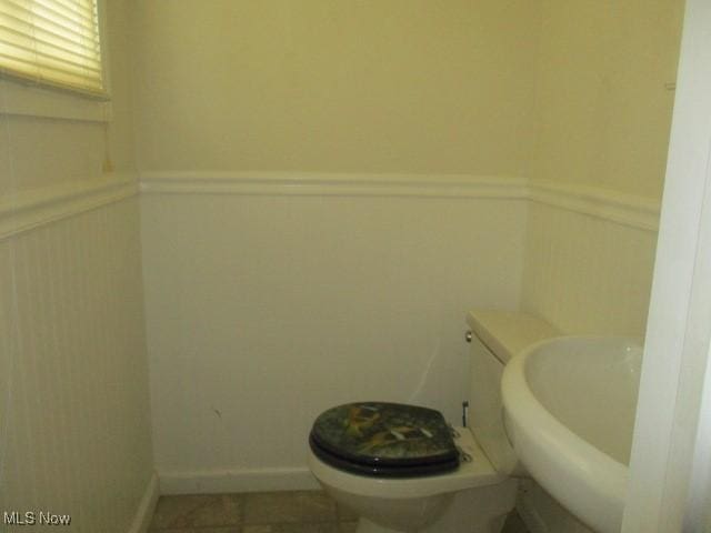 bathroom featuring wainscoting, a sink, and toilet