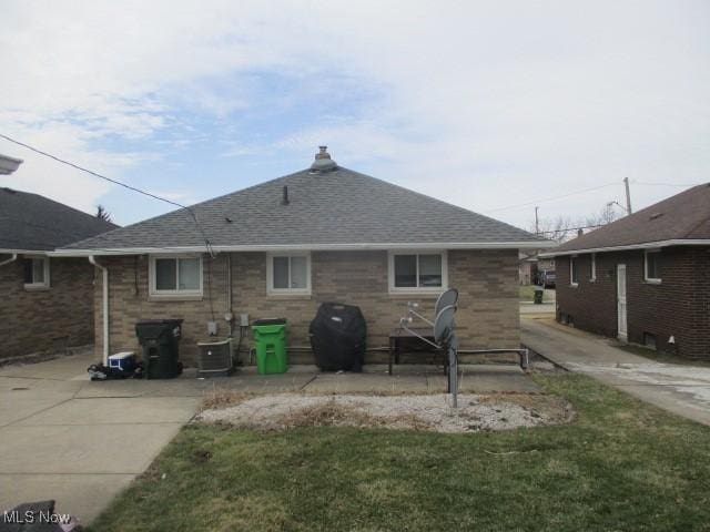 back of house with central AC, a patio, brick siding, and roof with shingles