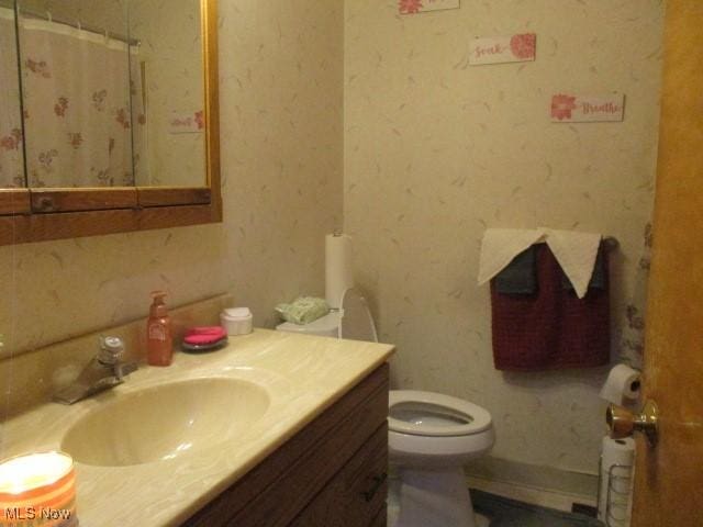 full bath with toilet, a shower with shower curtain, vanity, and wallpapered walls