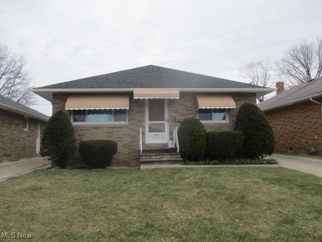 view of front of property featuring a front lawn and a shingled roof