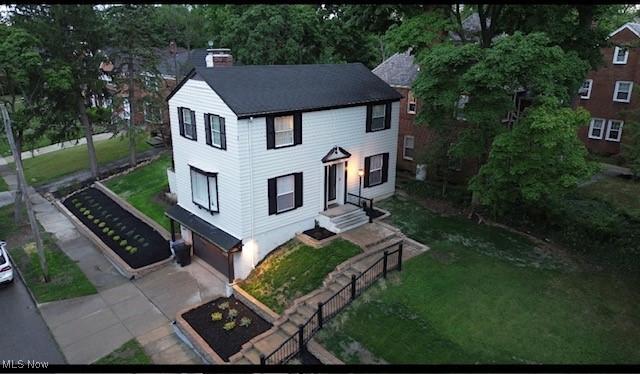 view of front of home with entry steps, concrete driveway, a chimney, and a front lawn