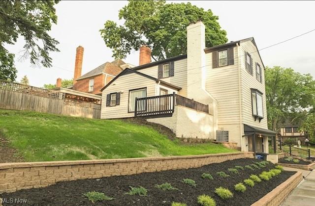 rear view of house with a chimney, fence, and a yard