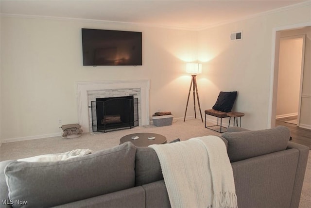 living room featuring baseboards, a fireplace with flush hearth, visible vents, and crown molding