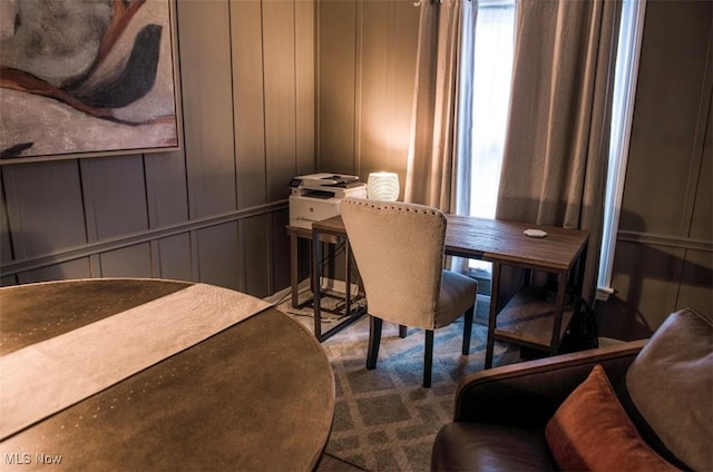 carpeted dining space featuring a decorative wall