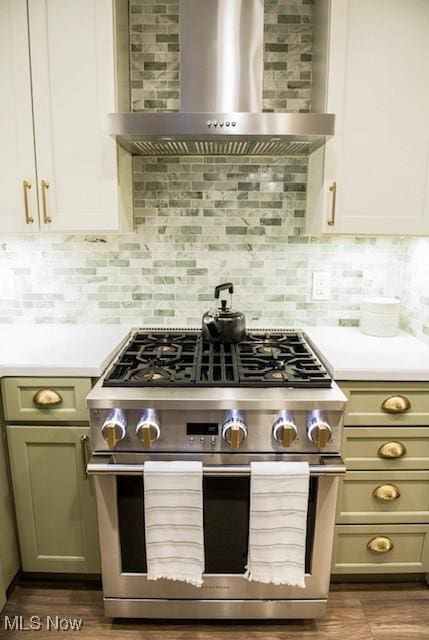 kitchen with light countertops, backsplash, wall chimney exhaust hood, and high end stainless steel range