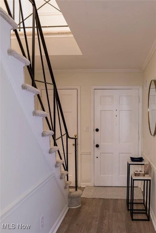 foyer with dark wood-style flooring, crown molding, stairway, and baseboards