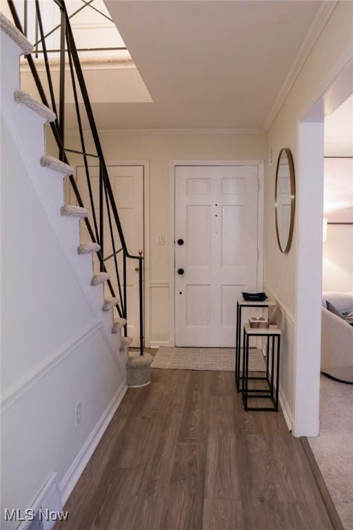 foyer featuring stairway, baseboards, ornamental molding, and dark wood finished floors