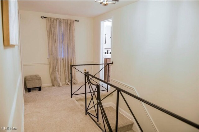 hall with carpet flooring, an upstairs landing, and baseboards