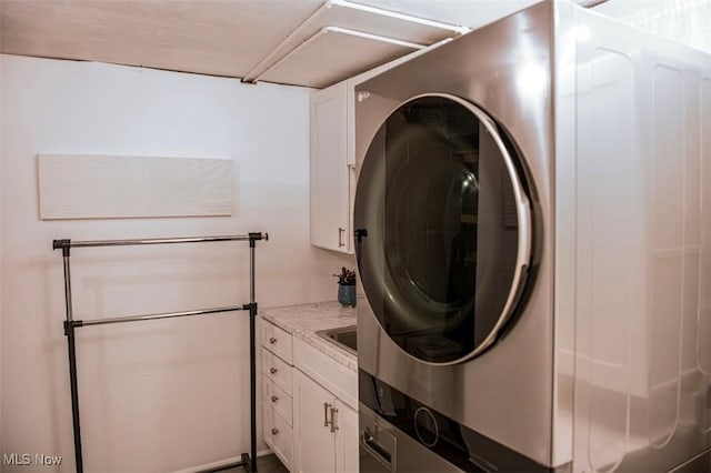 washroom featuring stacked washer and dryer and cabinet space