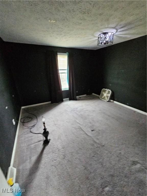 carpeted spare room with baseboards and a textured ceiling