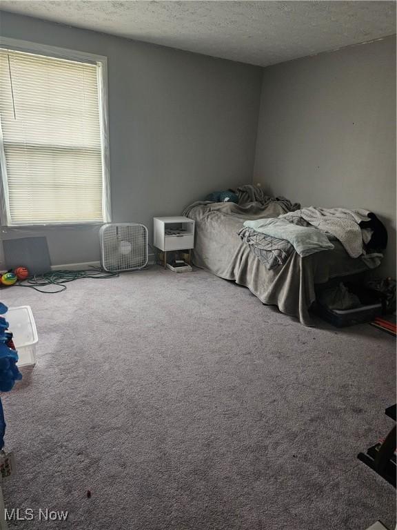 bedroom with carpet floors, a textured ceiling, and an AC wall unit