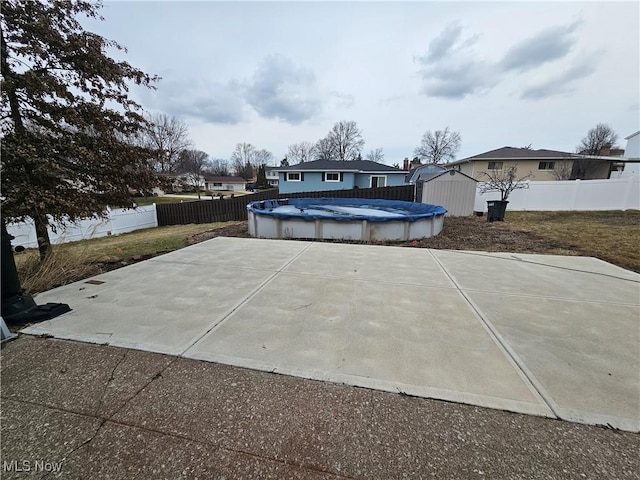 view of patio / terrace with a fenced in pool, a storage unit, a fenced backyard, and an outdoor structure