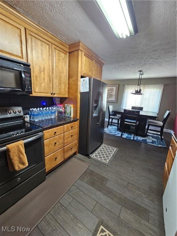 kitchen with dark wood finished floors, appliances with stainless steel finishes, a textured ceiling, and dark countertops