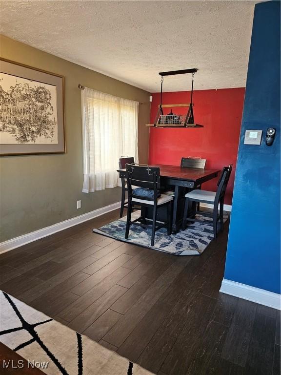 dining area featuring wood finished floors, baseboards, and a textured ceiling