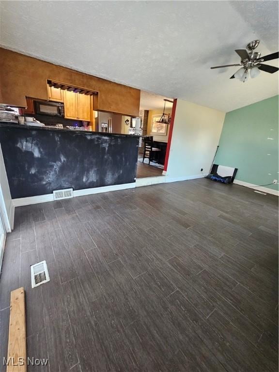 unfurnished living room with visible vents, baseboards, a ceiling fan, and dark wood-style flooring