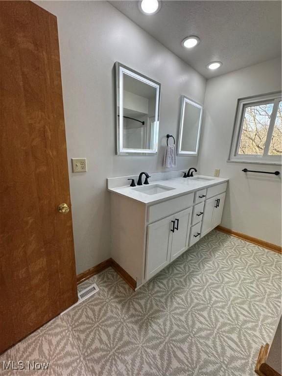 bathroom featuring baseboards, visible vents, a sink, and tile patterned floors