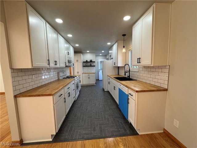 kitchen featuring butcher block counters, white appliances, a sink, and white cabinets