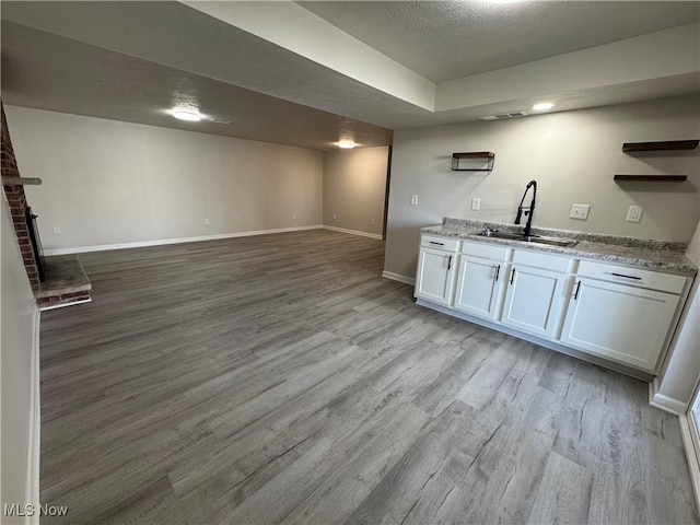 kitchen with light wood finished floors, baseboards, open floor plan, open shelves, and a sink