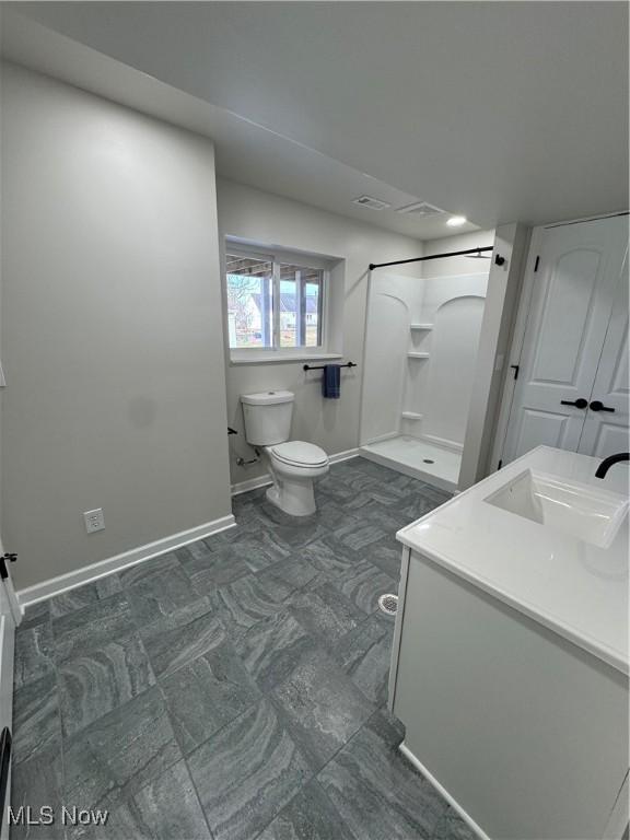 bathroom with toilet, visible vents, vanity, baseboards, and a shower stall