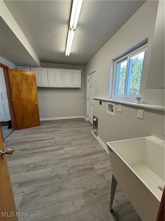 laundry area with washer hookup, cabinet space, a textured ceiling, wood finished floors, and baseboards