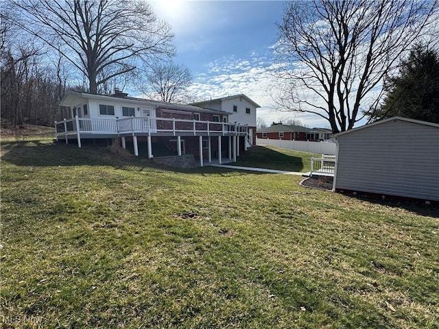 rear view of property featuring an outbuilding, fence, a deck, and a yard