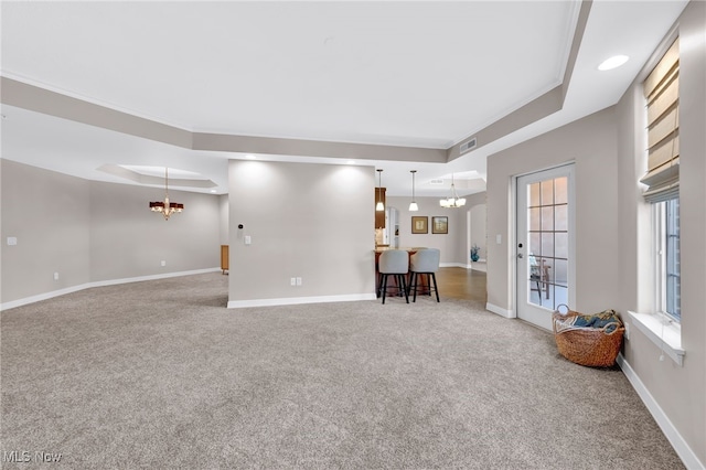 unfurnished living room featuring visible vents, baseboards, carpet floors, an inviting chandelier, and a raised ceiling