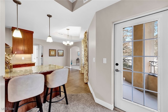 kitchen with visible vents, light stone counters, arched walkways, a peninsula, and baseboards