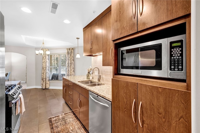 kitchen featuring light stone countertops, visible vents, a sink, stainless steel appliances, and a raised ceiling