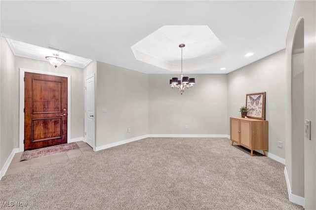 foyer with a tray ceiling, a notable chandelier, baseboards, and light carpet