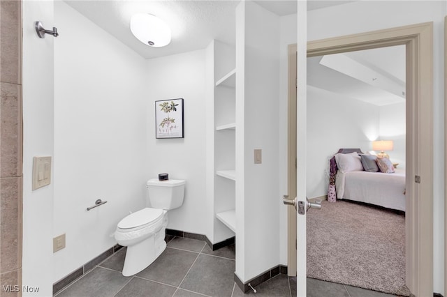 bathroom featuring tile patterned floors, toilet, baseboards, and ensuite bathroom