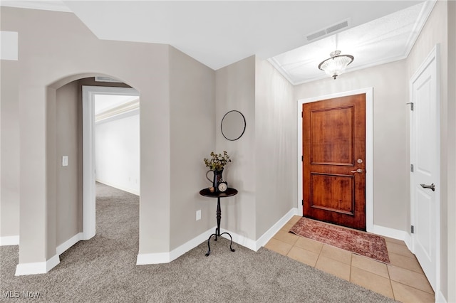 entrance foyer with visible vents, light carpet, arched walkways, light tile patterned flooring, and baseboards