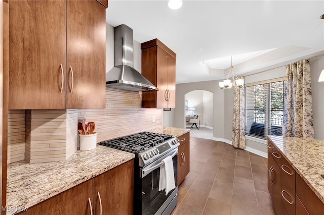 kitchen with gas stove, light stone countertops, a tray ceiling, decorative backsplash, and wall chimney exhaust hood