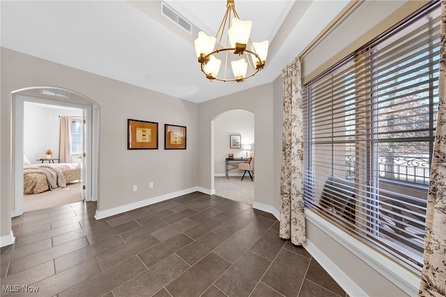 interior space with arched walkways, visible vents, a chandelier, and a wealth of natural light