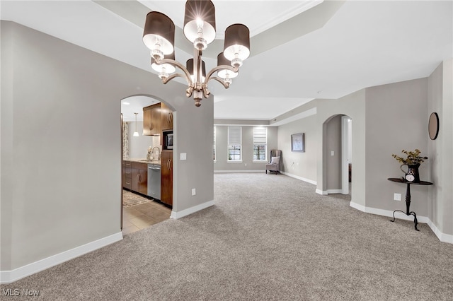 unfurnished living room featuring baseboards, arched walkways, a sink, light carpet, and a notable chandelier